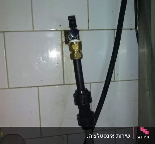 ברז פלסטיק מחובר לצינור על קיר אריחים